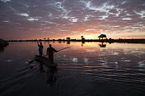 Fishermen in mokoro boat at sunrise, Chobe River, Namibia