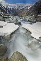 White river rapids flow over spring snow bank, Arthur's Pass National Park, Canterbury, New Zealand