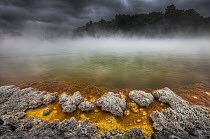 Champagne Pool as burst of sunshine lights up foreshore during day with blowing mist and heavy rain, Waiotapu Thermal Wonderland, Rotorua, New Zealand
