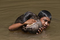 Giant River Otter (Pteronura brasiliensis) playing with Macushi boy, Karanambu Trust for re-introduction, Rupununi, Guyana