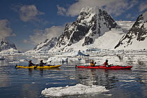 Kayakers paddling beneath Mount Scott at entrance to Lemaire Channel near Petermann Island, Antarctic Peninsula, Antarctica