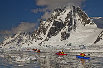Kayakers paddling beneath Mount Scott at entrance to Lemaire Channel near Petermann Island, Antarctic Peninsula, Antarctica