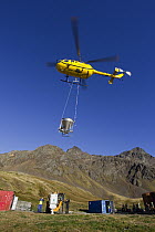Helicopter flying with bait bucket for South Georgia Heritage Trust Rat Eradication Project, Grytviken, South Georgia Island