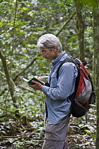 Chimpanzee (Pan troglodytes) researcher, David Watts, recording field observations, western Uganda