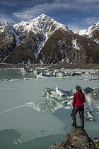 Woman overlooks frozen lake, Tasman Glacier, Mount Cook National Park, New Zealand