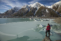 Woman overlooks frozen lake, Tasman Glacier, Mount Cook National Park, New Zealand