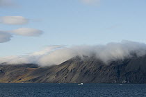 Clouds hugging the tops of shoreline mountains, Wrangel Island, Russia
