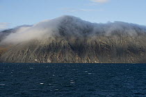 Clouds hugging the tops of shoreline mountains, Wrangel Island, Russia