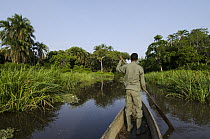 Man paddling canoe down Lekoli River, Democratic Republic of the Congo