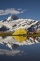 Hikers near their lakeside tent, Cascade Saddle, Mount Aspiring National Park, Otago, New Zealand