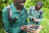 Anti-poaching snare removal team members, John Okwilo and Godfrey Nyesiga, noting animal sign in rainforest, Kibale National Park, western Uganda