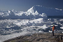 Tourist and icebergs, Ilulissat, Greenland
