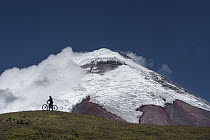 Cyclist near snow-covered peak, Cotopaxi Volcano, Cotopaxi National Park, Andes, Ecuador