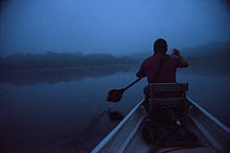 Guide paddling canoe at dawn, Amazon, Ecuador