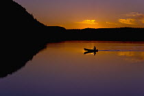 Person canoeing on lake at sunset, John Lake, Boundary Waters Canoe Area Wilderness, Minnesota