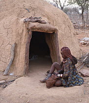 Himba woman in front of her hut, Kaokoveld Desert, Namibia