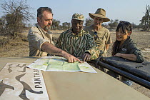 African Lion (Panthera leo) biologists, Luke Hunter, Jake Overton, and Kim Young-Overton, discussing poaching activities with park scout, Timbo Frackson, Kafue National Park, Zambia