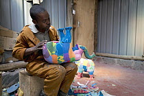Artist working on sculptures made from reclaimed flip-flops, Ocean Sole, Nairobi, Kenya