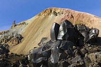 Rhyolite mountains with fields of shiny black basalt boulders, Landmannalaugar, Fjallabak Nature Reserve, Iceland