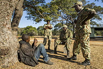 Arrested poacher being questioned by anti-poaching commanders, Kafue National Park, Zambia