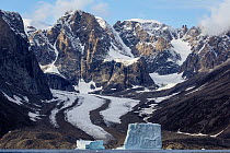 Icebergs along coastal mountains and glacier, Scoresby Sound, Greenland