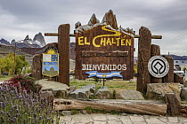 Welcoming sign for town with peaks, mirroed by mountains in background, El Chalten, Patagonia, Argentina