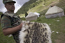 Snow Leopard (Uncia uncia) a member of the Gruppa Bars Snow Leopard anti-poaching team with a pelt which has been confiscated, Kyrghyzstan