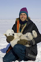 Polar Bear (Ursus maritimus) reseacher Nick Lunn holds tranquilized three to four month old cub during examination, vulnerable, Wapusk National Park, Manitoba, Canada
