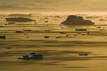 Many icebergs drifting in the Arctic at midnight, end of June, mid summer night, Disko Bay, Greenland