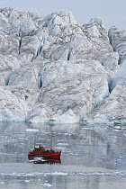 Tourist boat in front of large iceberg at midnight, end of June, mid-summer night, Greenland
