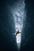 Ice climber crossing crevasse, Columbia Icefield, Jasper National Park, Alberta, Canada