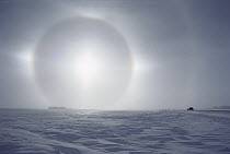 Sundogs, also known as mock sun, with car on the horizon above a snow field, Minnesota