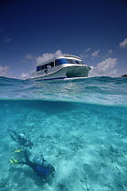 Scuba divers Leslie Davies and Alison Jenkin swim beneath new catamaran speedboat, British Virgin Islands