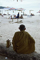 Buddhist Monk and European tourists on beach at Phuket, Thailand