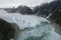 Aerial view of receding glacier in glacial valley showing lateral moraines on either side, southeast Alaska