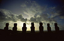 Giant Moai statues at A Kivi silhouetted against stormy sky in southern part of Easter Island