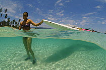 Windsurfer in sea bringing surfboard ashore. Philippines