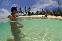 Tourist relaxing in shallow sea, with people on beach, Philippines