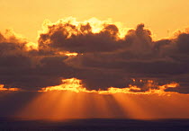 Sun rays through clouds at dawn over the Atlantic sea, St Kilda, Scotland, UK