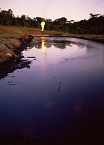Burning waste oil beside pool of oil on oil platform, Cuyabeno NP, Ecuador