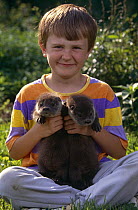 Boy with two Eurasian River otter cubs {Lutra lutra} Poland