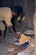 Mahout making domestic elephant cake chapattis on open fire, Bandhavgarh NP, Madhya Pradesh, India