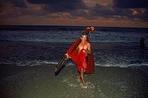 Man with red net on beach at night, after fishing for larval penaeid shrimp, Western Ecuador