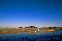 Tourists on safari in Makoro (dug out canoe) Okavango Delta, Botswana.