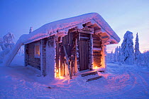 Cosy looking hut surrounded by snow laden trees in winter, Finland