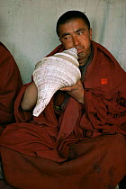 Buddhist monk blows a horn made from large shell, Nepal