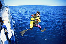 Scuba diver jumping off boat into the sea Bahamas