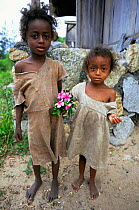 Two Malagasy children holding posie of Rosy Periwinkles {Catharanthus roseus}, southern Madagascar