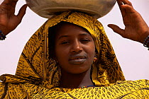 Portrait of Falani woman in traditional clothing, with bowl on her head, Mali, West Africa