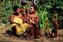 Local women feeding black lemurs, faces painted with sandlewood paste, Nosy Komba Island, Madagascar